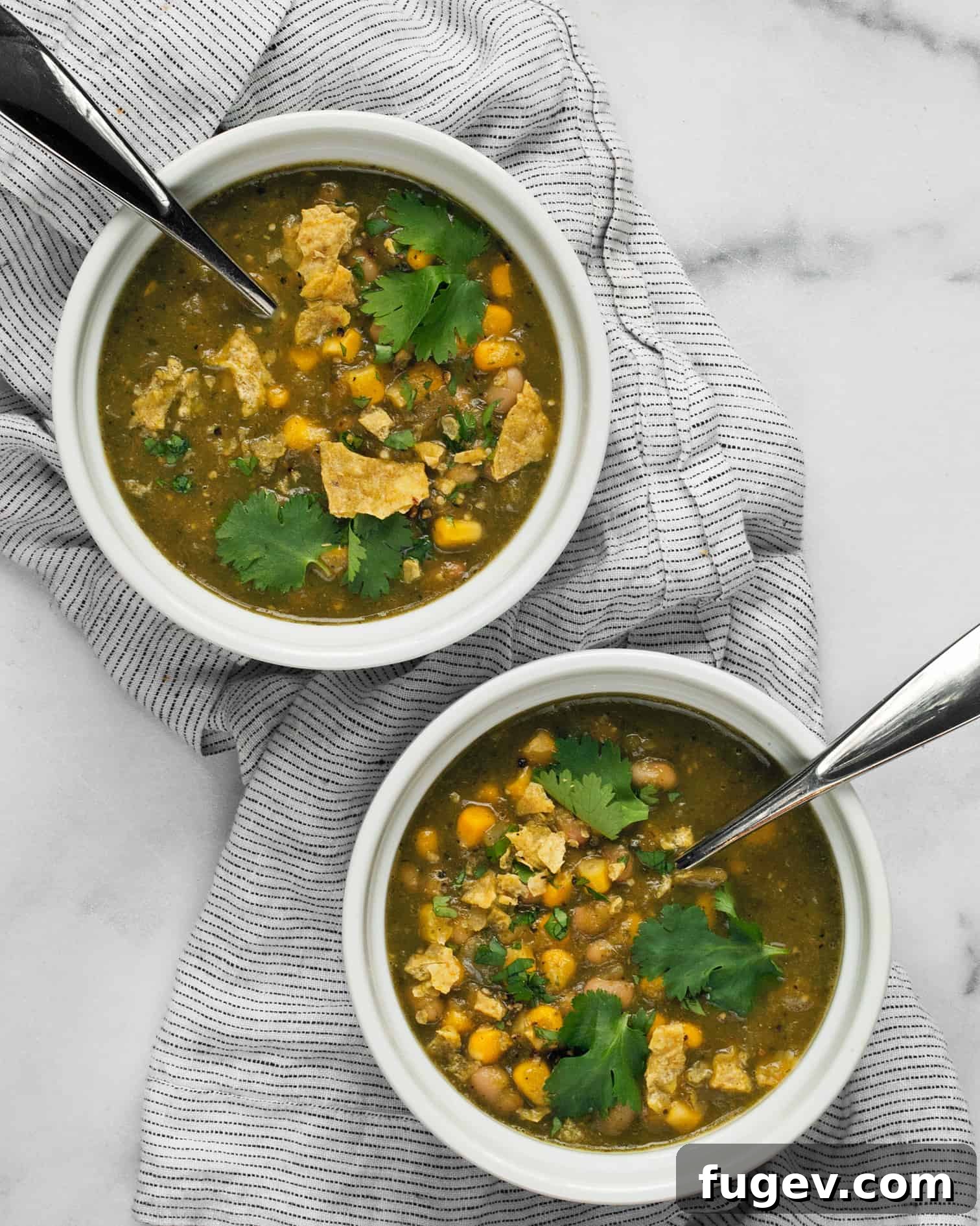 Flavorful Chile Verde with Creamy White Beans 7 Two bowls of vegan chile verde with white beans and corn, garnished with cilantro and tortilla chips, ready to eat.