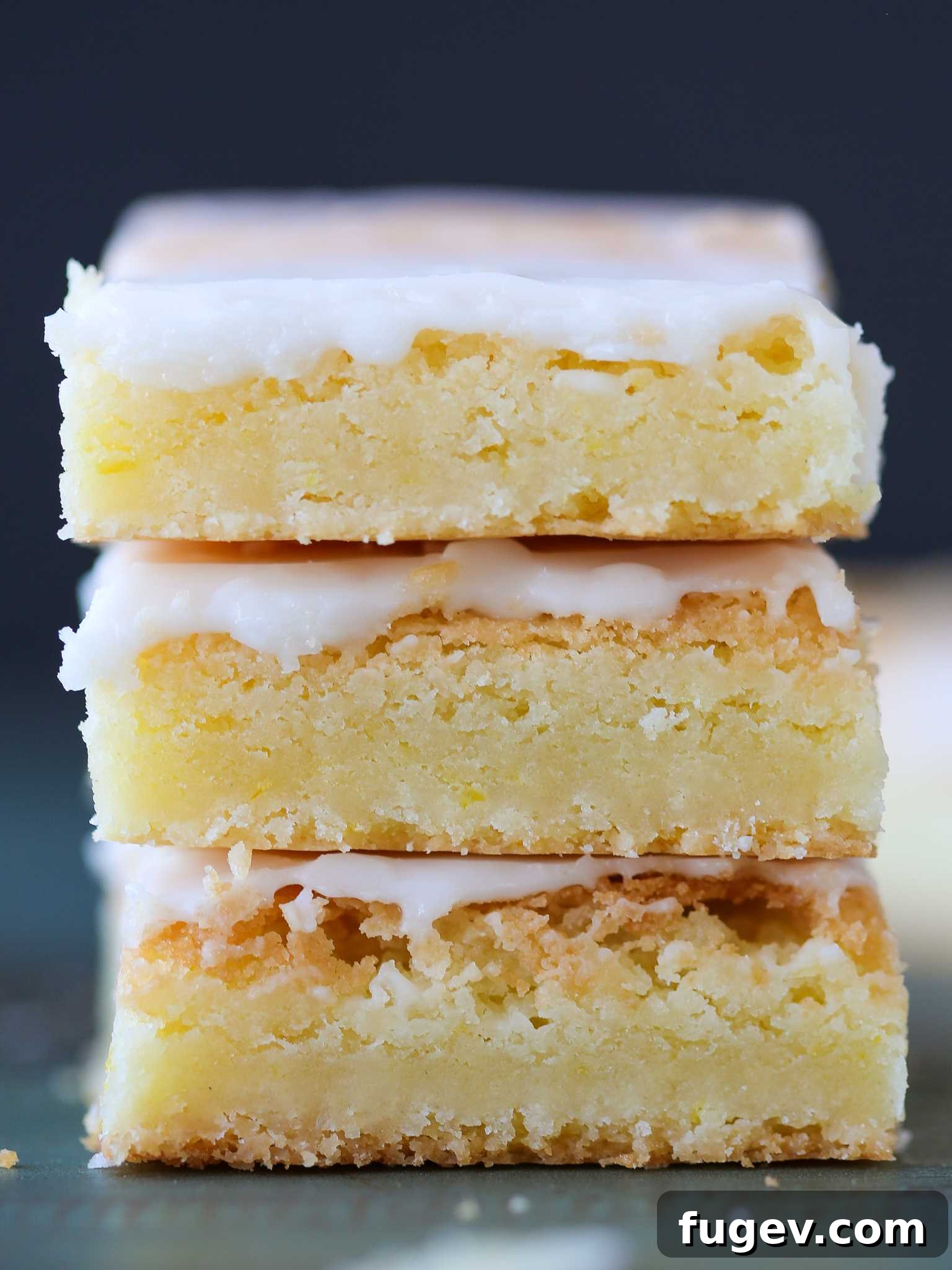 Golden Lemon Squares 2 Stacked Lemon Blondies on a white plate, showcasing their bright color and soft texture, with a hint of lemon zest.