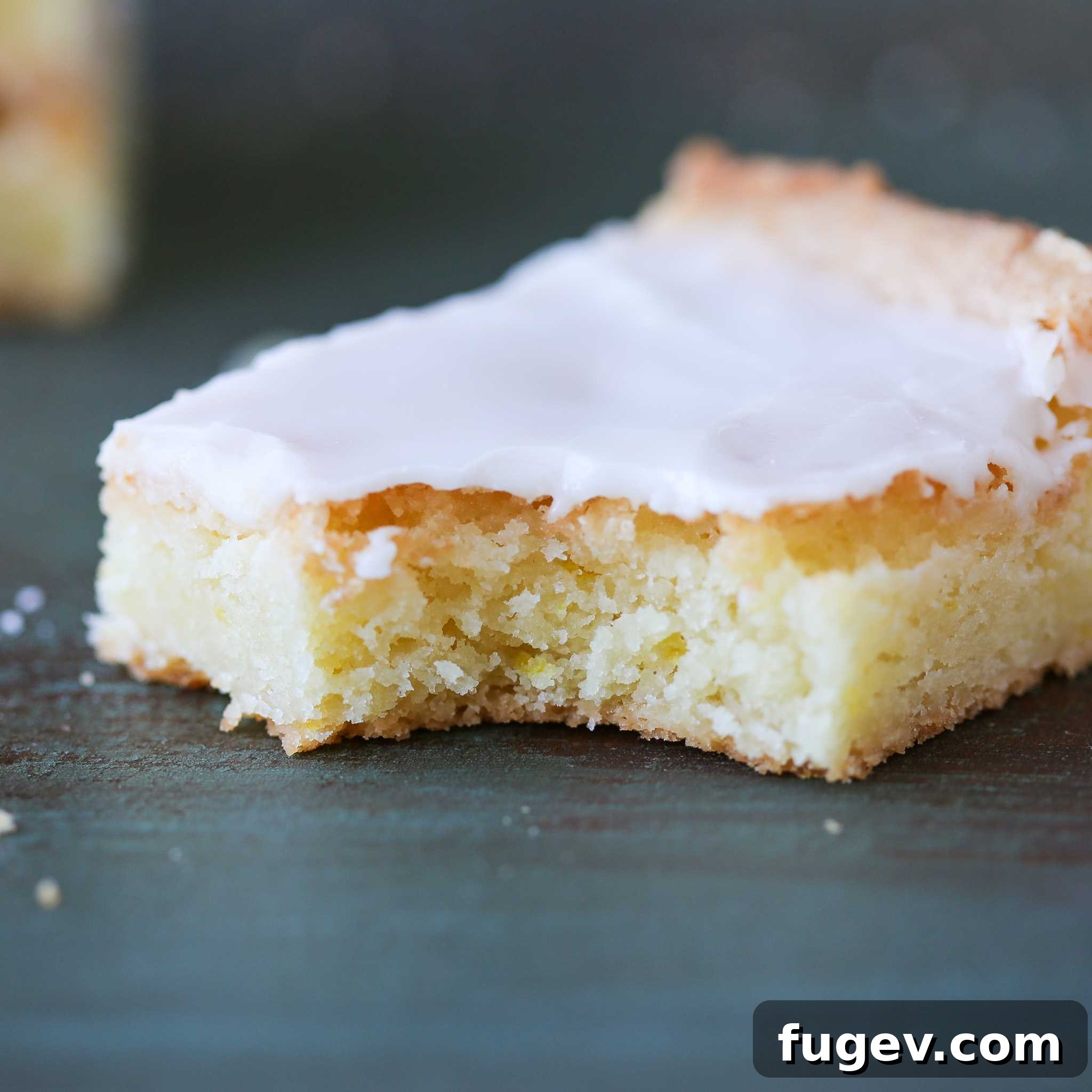 Golden Lemon Squares 4 A perfectly portioned serving of Lemon Blondies with a fork, showing the soft interior and glossy glaze, ready to be eaten.