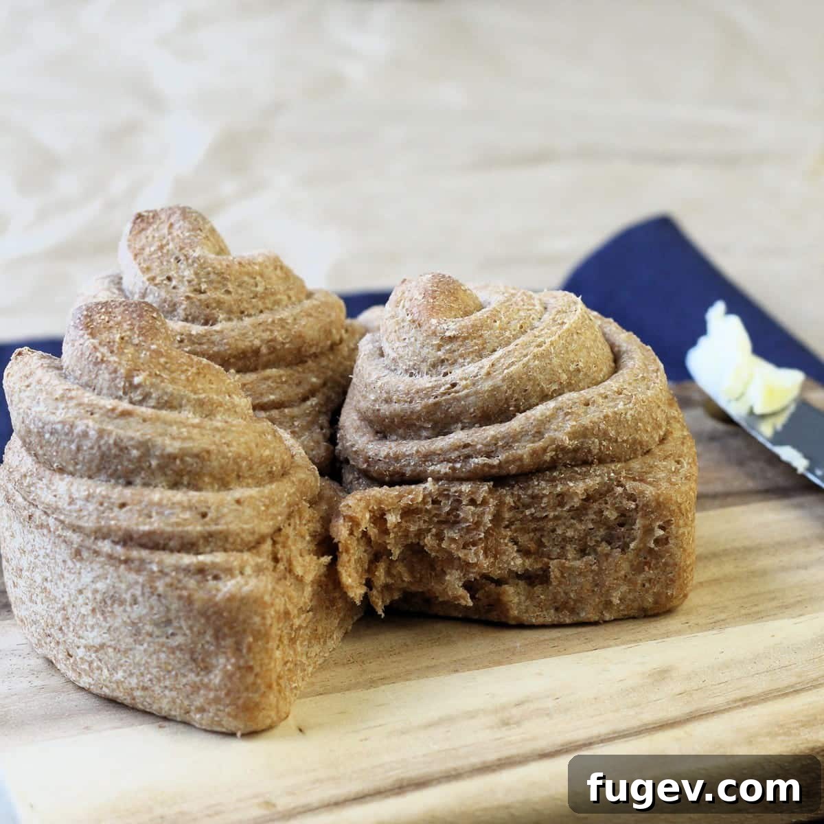Rustic Wheat Rolls 4 Several wholesome whole wheat rolls rest casually on a wooden board, showcasing their rustic homemade finish and inviting texture.