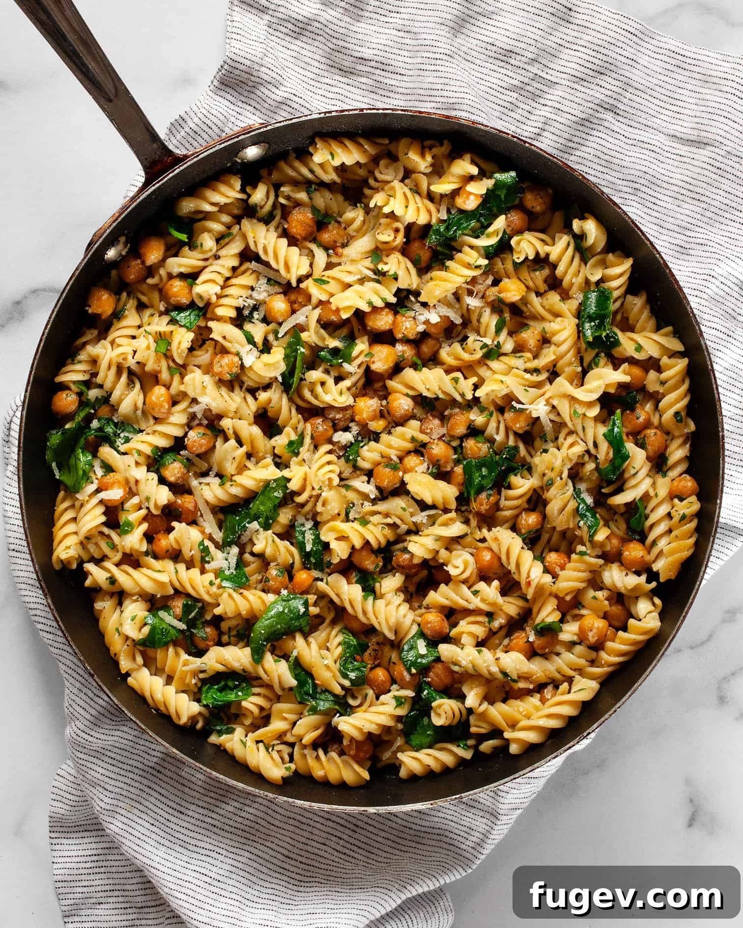 Hearty Spinach Chickpea Pasta 7 A large skillet filled with chickpea pasta, wilted spinach, and golden chickpeas, ready to be served.