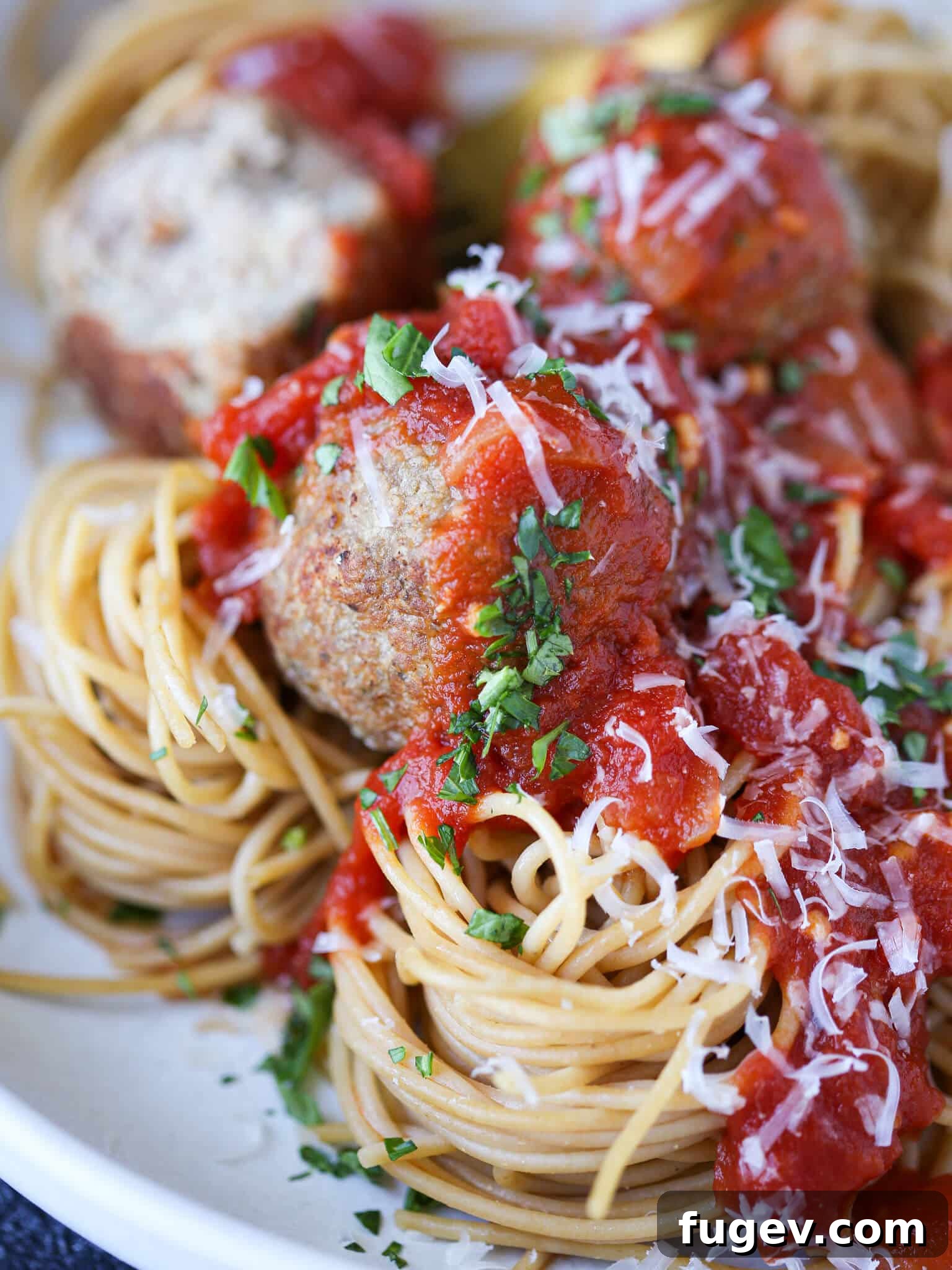 Juicy Baked Turkey Meatballs 2 Baked turkey meatballs served in a bowl of spaghetti with fresh herbs.