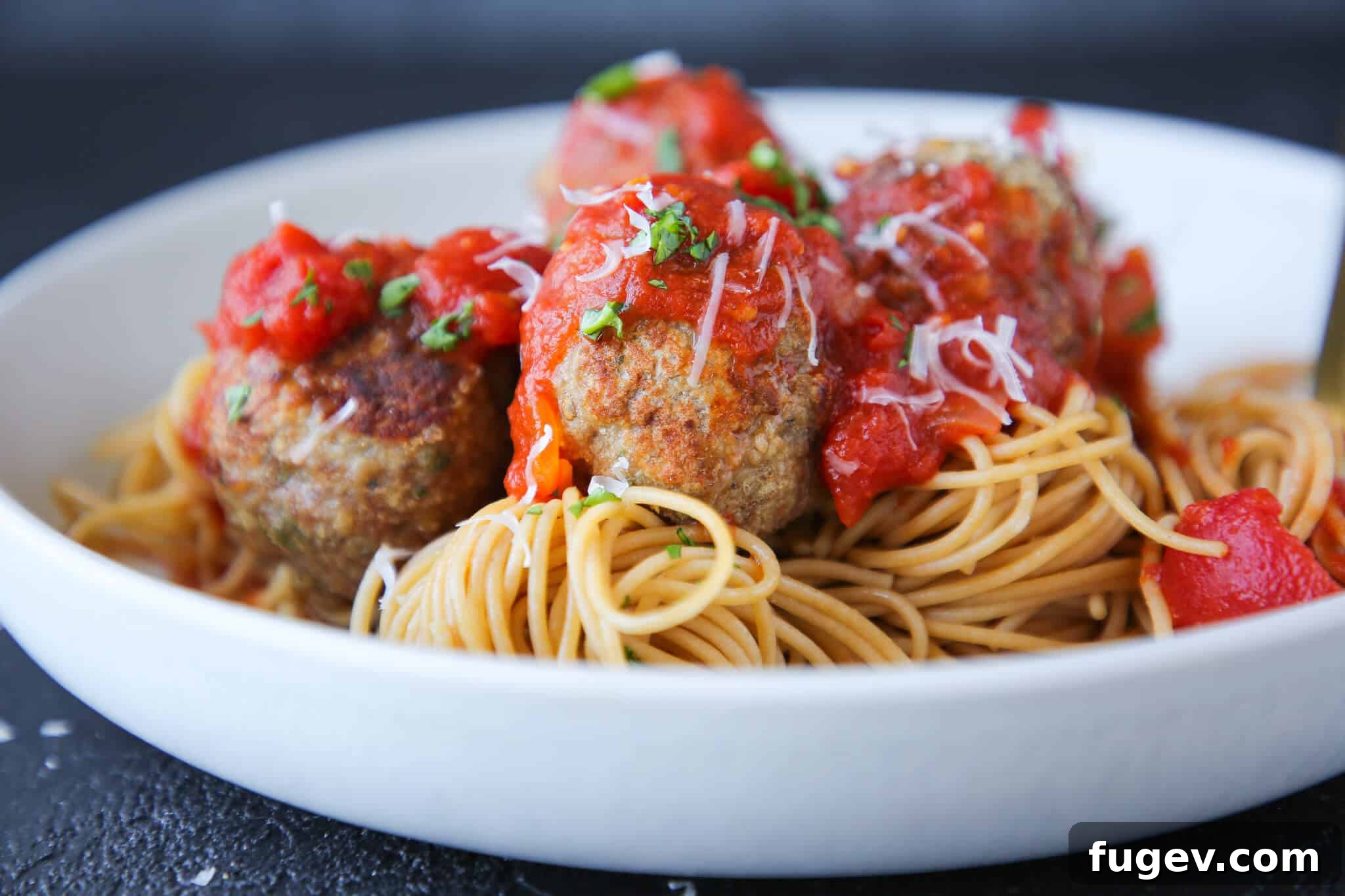 Juicy Baked Turkey Meatballs 4 Baked turkey meatballs served in a white pasta dish with fresh basil garnish.