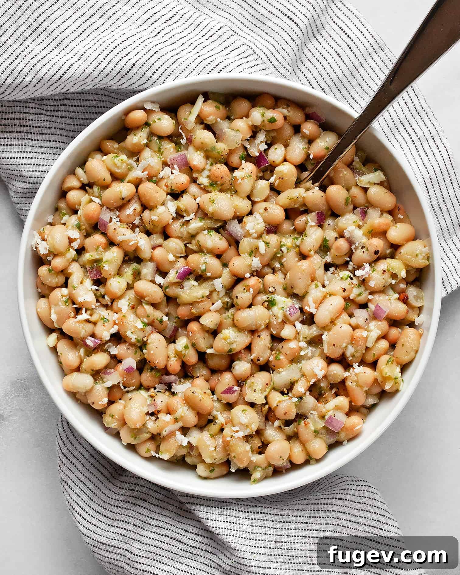 Zesty Lemon Basil White Bean Salad 2 A beautifully presented white bean salad in a rustic bowl with a serving spoon, garnished with fresh basil leaves.