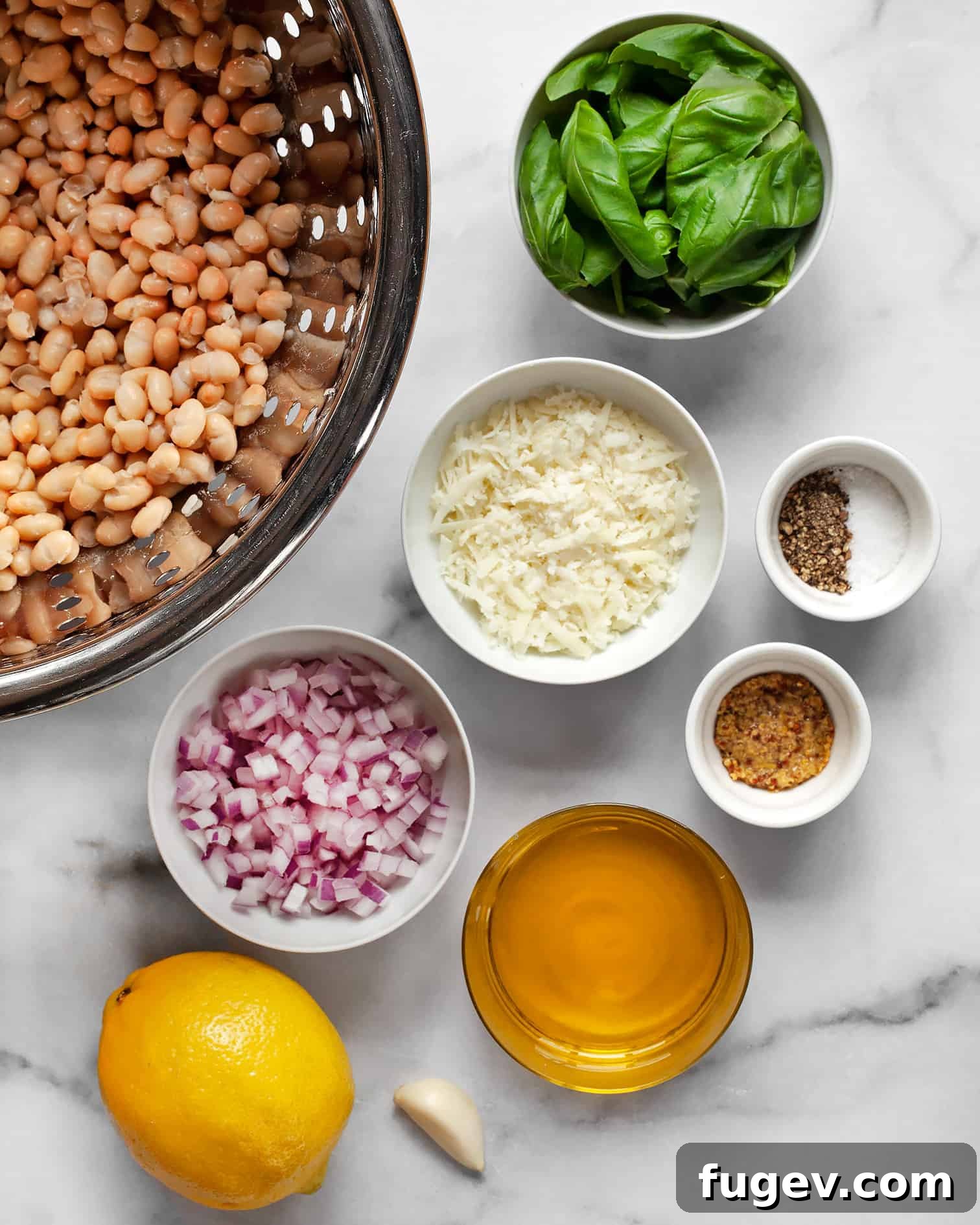 Zesty Lemon Basil White Bean Salad 3 Fresh ingredients laid out for white bean salad: canned white beans, sliced red onions, a wedge of Pecorino cheese, fresh basil, a head of garlic, a lemon, and a bottle of olive oil.