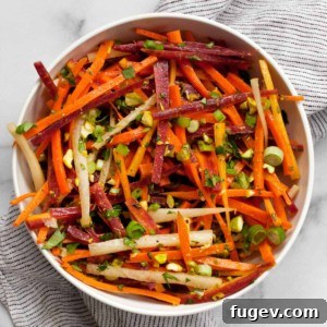 Carrot salad in a small bowl, garnished with fresh herbs and pistachios, ready to be enjoyed.