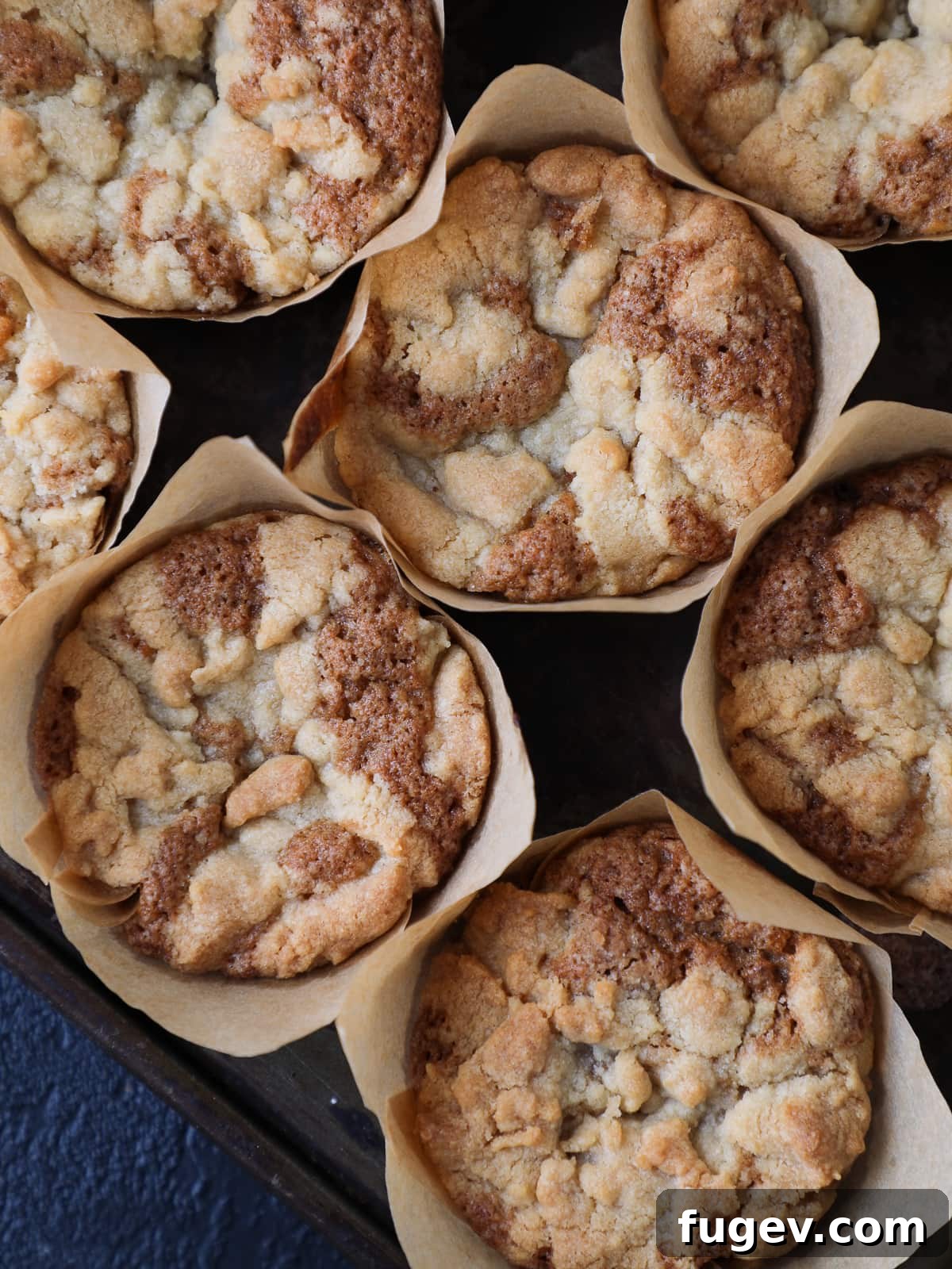 Luscious Peach Muffins 4 Group of peach muffins cooling on a wire rack, showcasing their golden domed tops and visible warm fruit baked into each one.