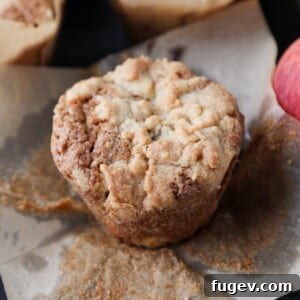 Fresh muffin made with peaches, resting on parchment with a golden top and crisp edges, ready to be enjoyed.
