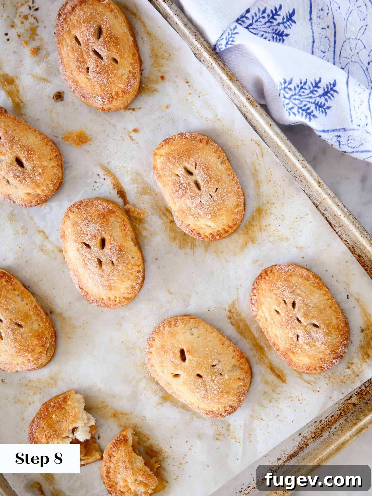 Flaky Apple Turnovers 12 Freshly baked apple hand pies on a baking sheet, golden brown with bubbling filling.