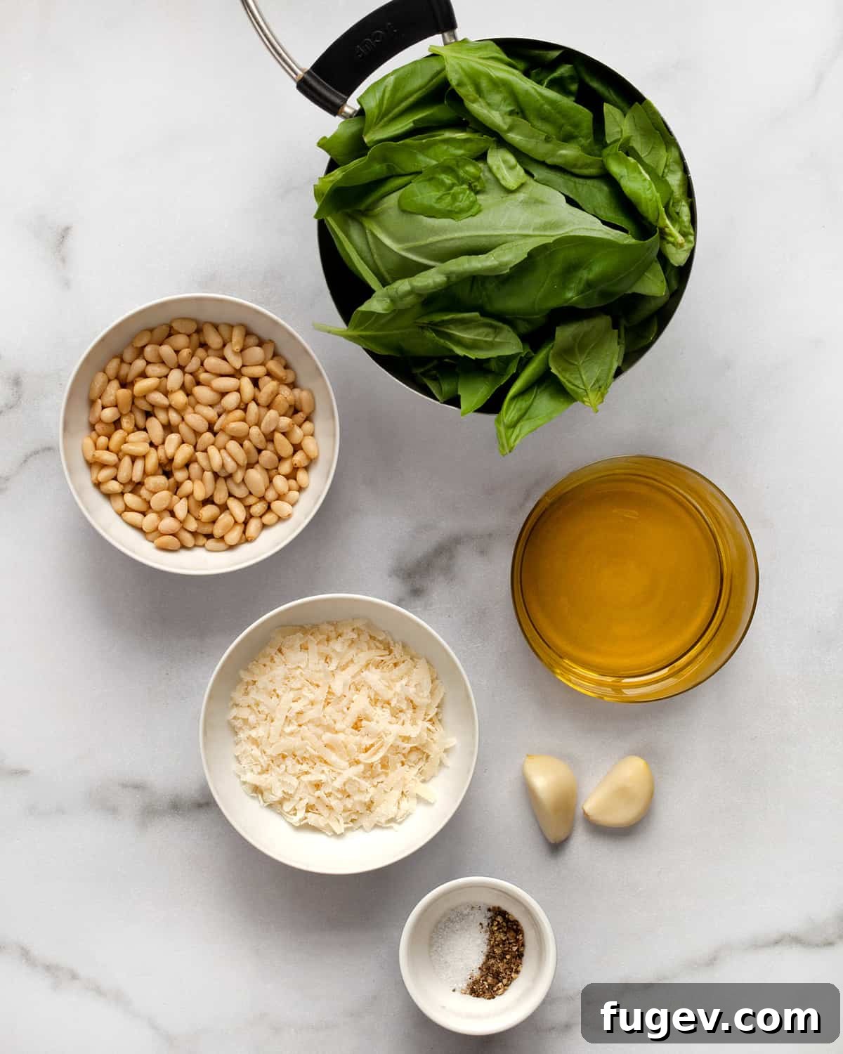 Homemade Pesto Perfection 3 A vibrant flat lay showcasing all the fresh ingredients needed for homemade pesto, including bright green basil leaves, plump pine nuts, garlic cloves, a block of Parmesan cheese, and a bottle of olive oil, alongside salt and pepper.
