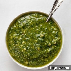 Basil pesto in a small bowl with a spoon, highlighting its vibrant color.