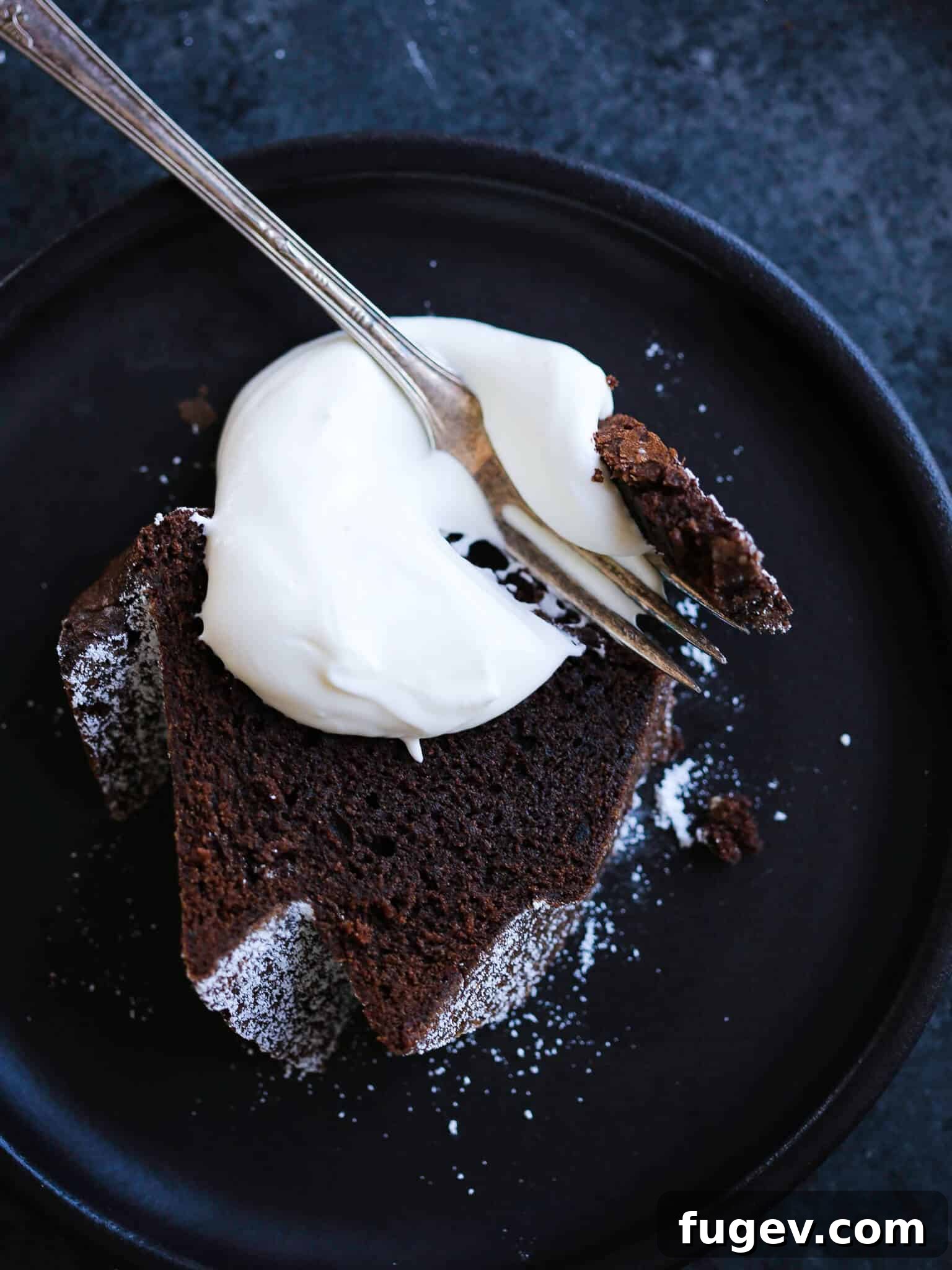 Decadent Chocolate Pound Cake 2 The best chocolate pound cake sliced with whipped cream on black plate.