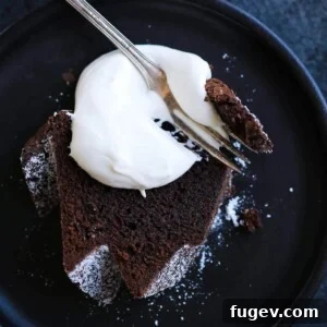 A slice of chocolate pound cake with whipped cream dolloped on top.