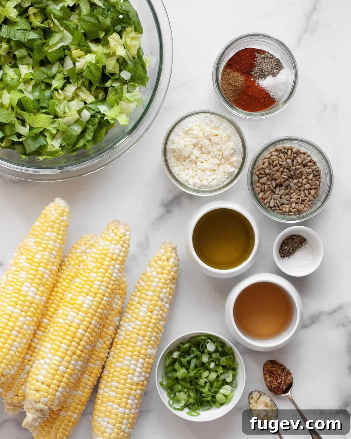 Smoky Roasted Corn Salad 3 All the fresh ingredients laid out for roasted corn salad: corn on the cob, chopped romaine, crumbled feta, sliced scallions, sunflower seeds, and small bowls of spices, olive oil, and white wine vinegar for the dressing.