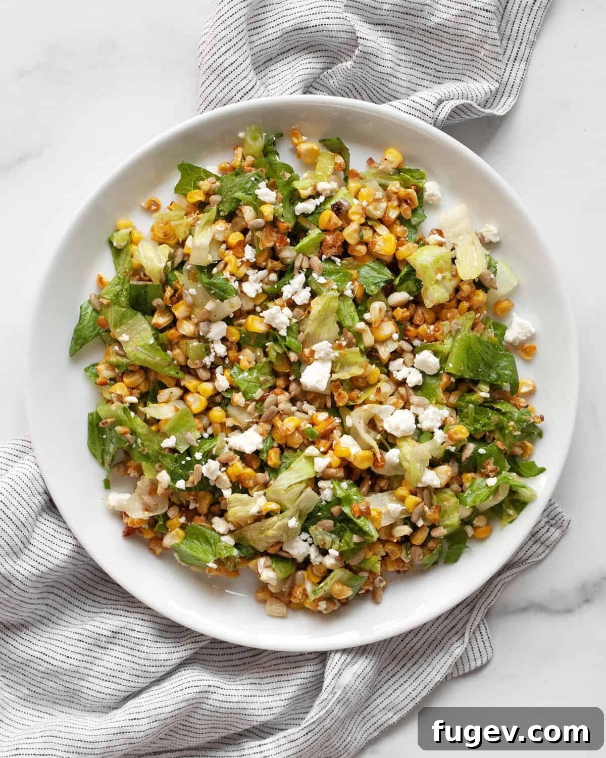 Smoky Roasted Corn Salad 7 A single serving of roasted corn salad artfully arranged on a white plate, showcasing its colorful ingredients.