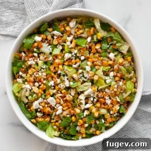 Chopped salad with roasted corn, romaine, feta and scallions in a bowl.