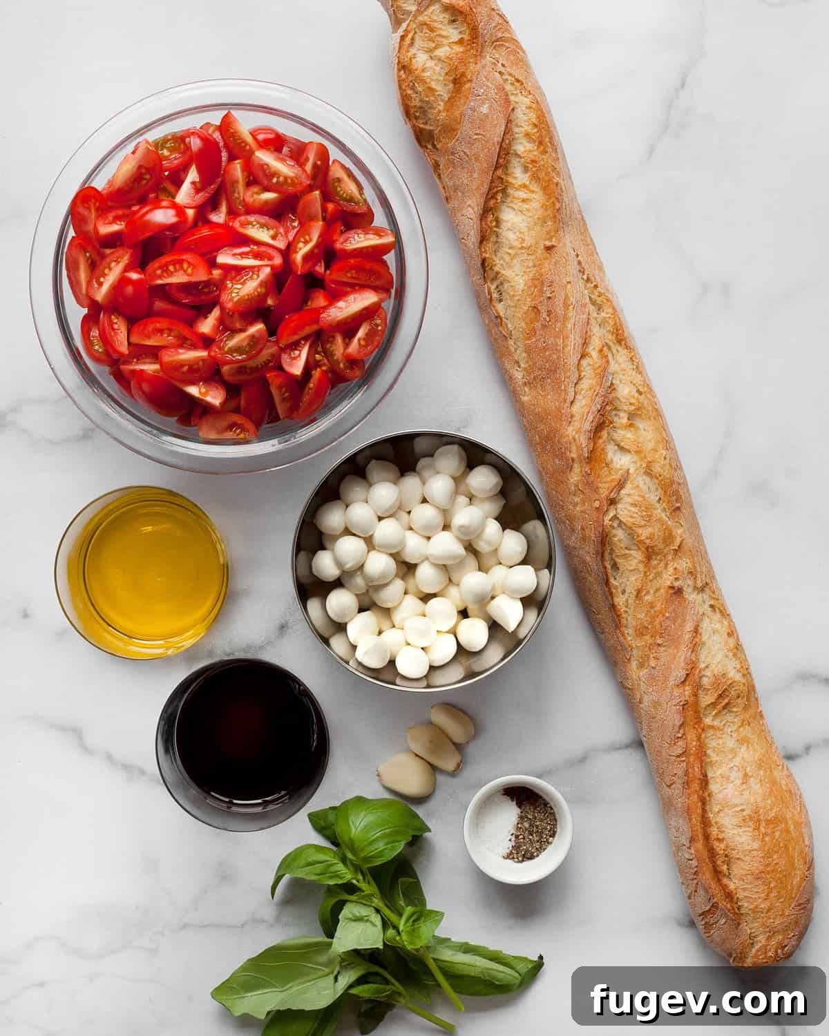 Caprese Bruschetta with Juicy Tomatoes and Creamy Mozzarella 3 A flat lay image displaying all the fresh ingredients needed for Caprese bruschetta: ripe tomatoes, fresh mozzarella pearls, a bottle of olive oil, balsamic vinegar, a head of garlic, and a bunch of fresh basil leaves on a rustic wooden board.