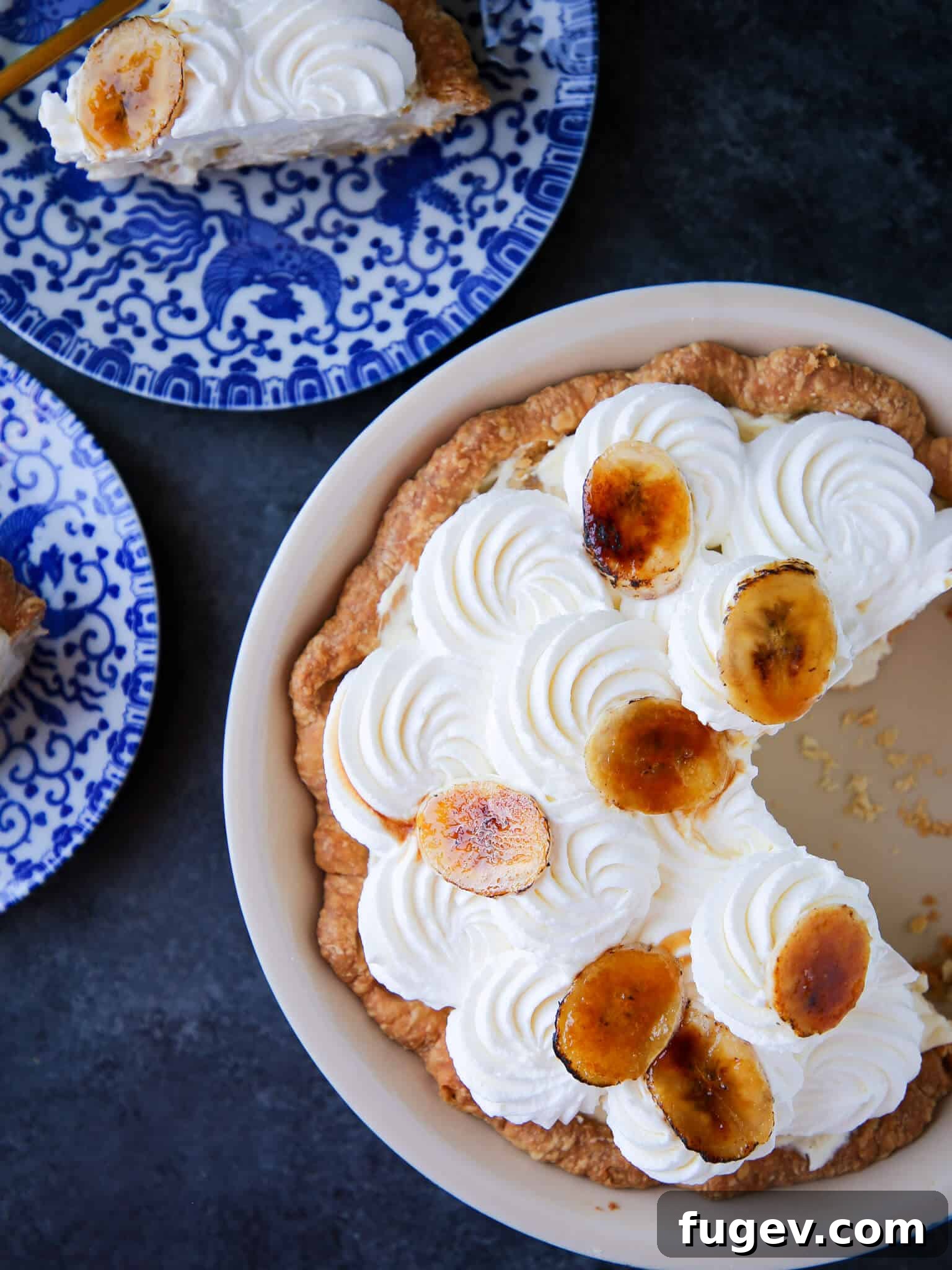 Classic Banana Cream Pie Slice A perfectly sliced Banana Cream Pie showing layers of crust, banana, pastry cream, and whipped cream, served on a vintage blue plate.