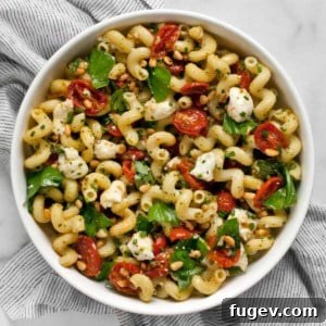 Pesto pasta salad with roasted tomatoes and mozzarella in a bowl.