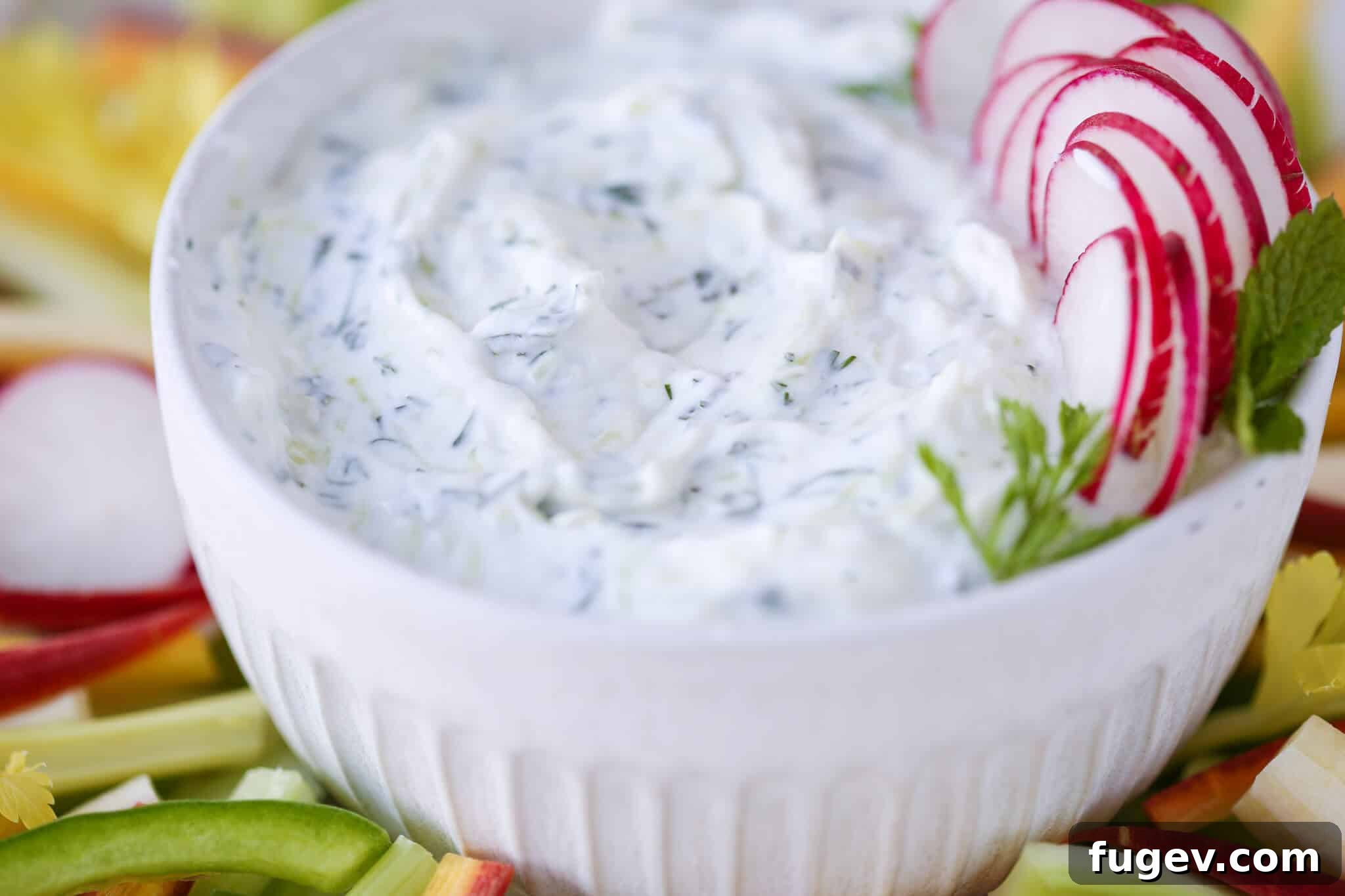 Refreshing Greek Tzatziki 4 Stunning overhead view of tzatziki dip artfully swirled in a white bowl, ready to be served.