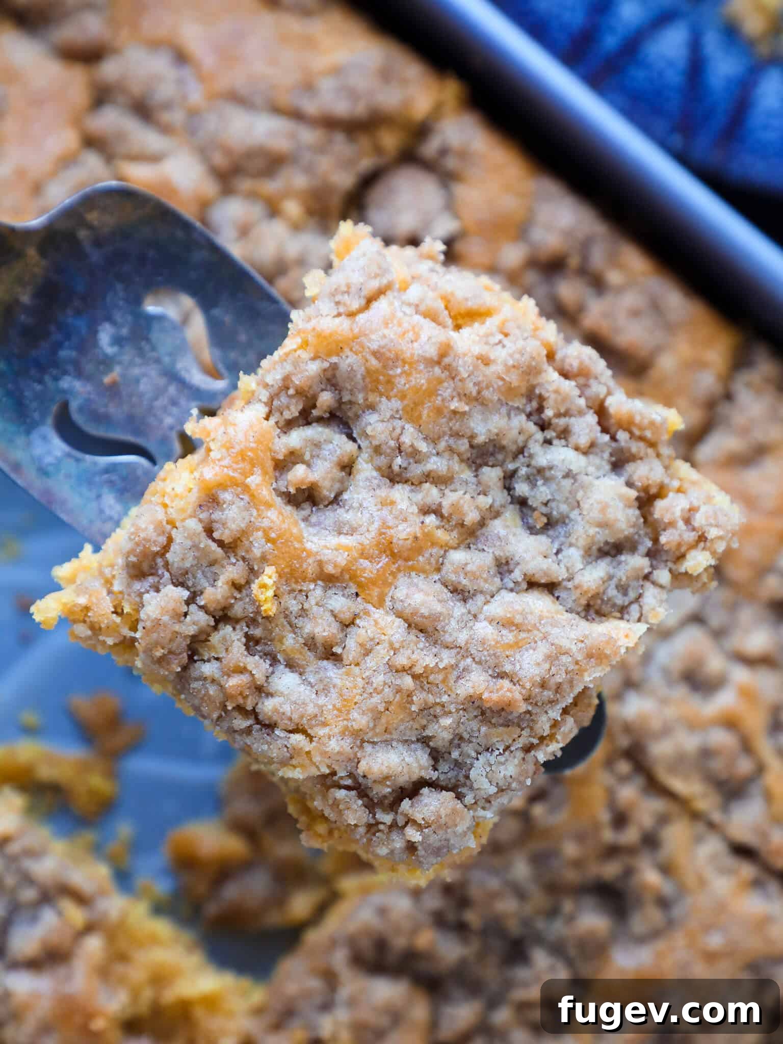 Spiced Pumpkin Streusel Cake 3 A slice of pumpkin coffee cake being lifted from the baking dish, showcasing its perfect layers and crumb topping.