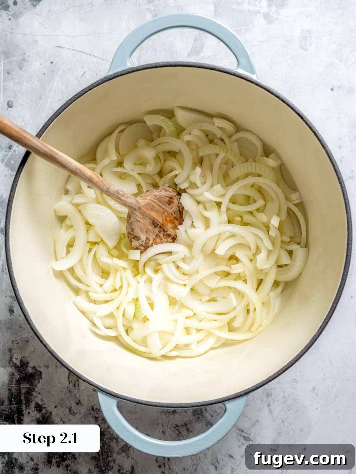 Juicy Homemade Turkey Burgers 6 Sliced onions beginning to cook down in a Dutch oven with a wooden spoon, stirring them gently.