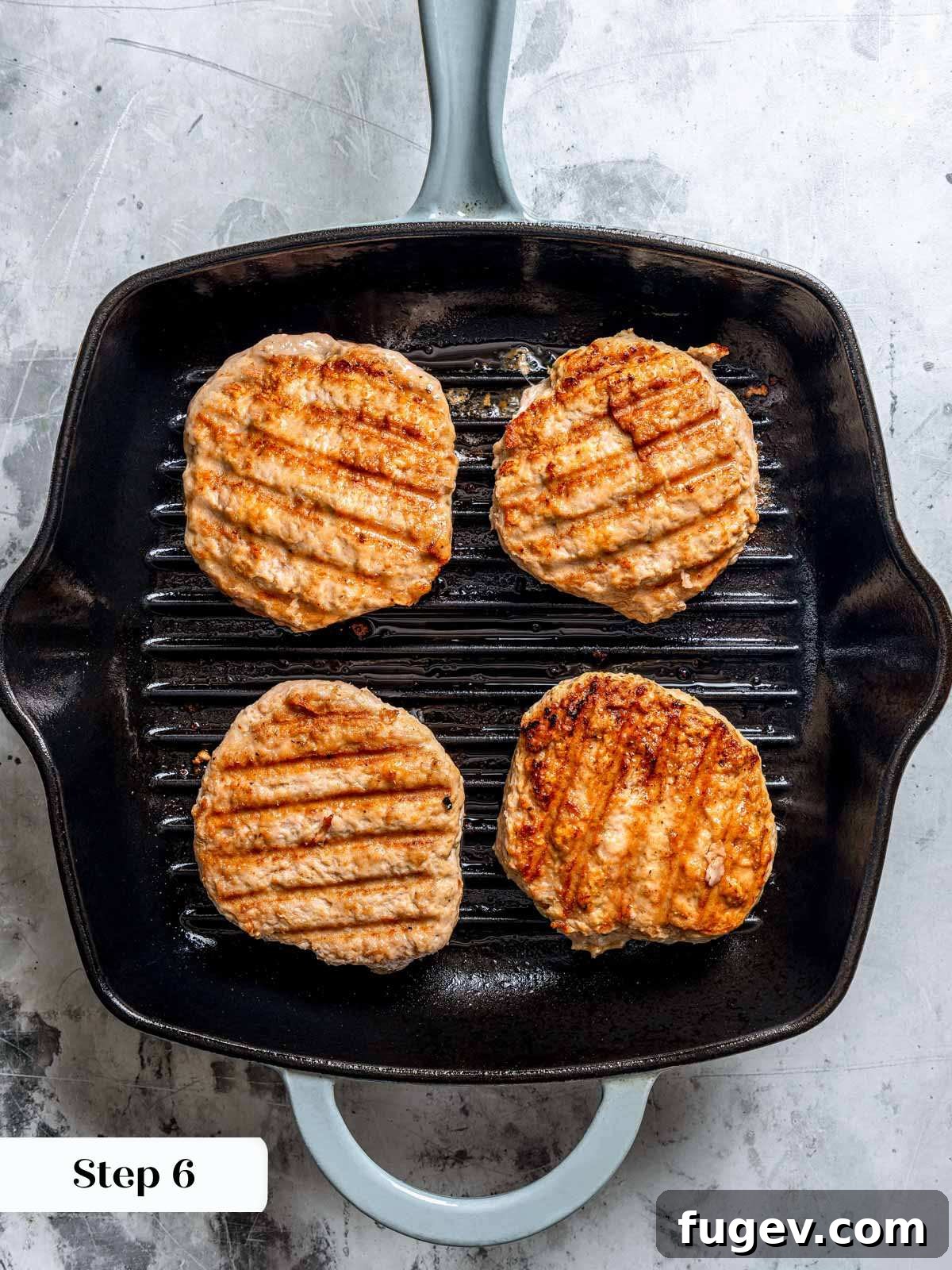 Juicy Homemade Turkey Burgers 10 Four turkey burgers sizzling and cooking in a grill pan, showing a nice sear on the surface.