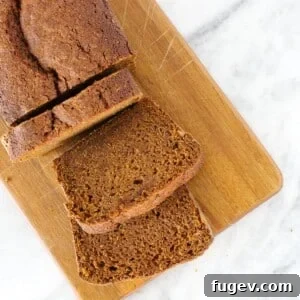 Pumpkin bread slices on a wooden board, set on a marble counter
