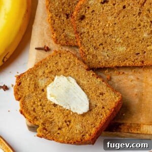 Slice of pumpkin banana bread with melting butter on a warm crumb