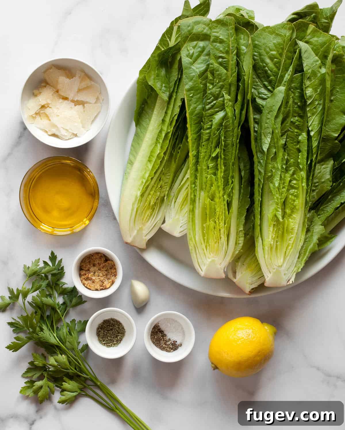 Fire Kissed Romaine 2 Ingredients including romaine, parmesan, olive oil, lemon, garlic, salt and pepper laid out on a wooden board.