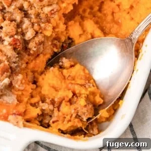 35 Essential Thanksgiving Sides 16 Sweet potato casserole being served with a spoon, showing its crunchy topping.
