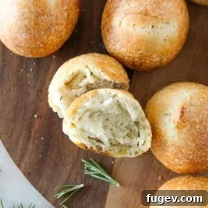 35 Essential Thanksgiving Sides 6 Rosemary Sourdough Rolls presented on a rustic wooden tray, highlighting their golden crust.
