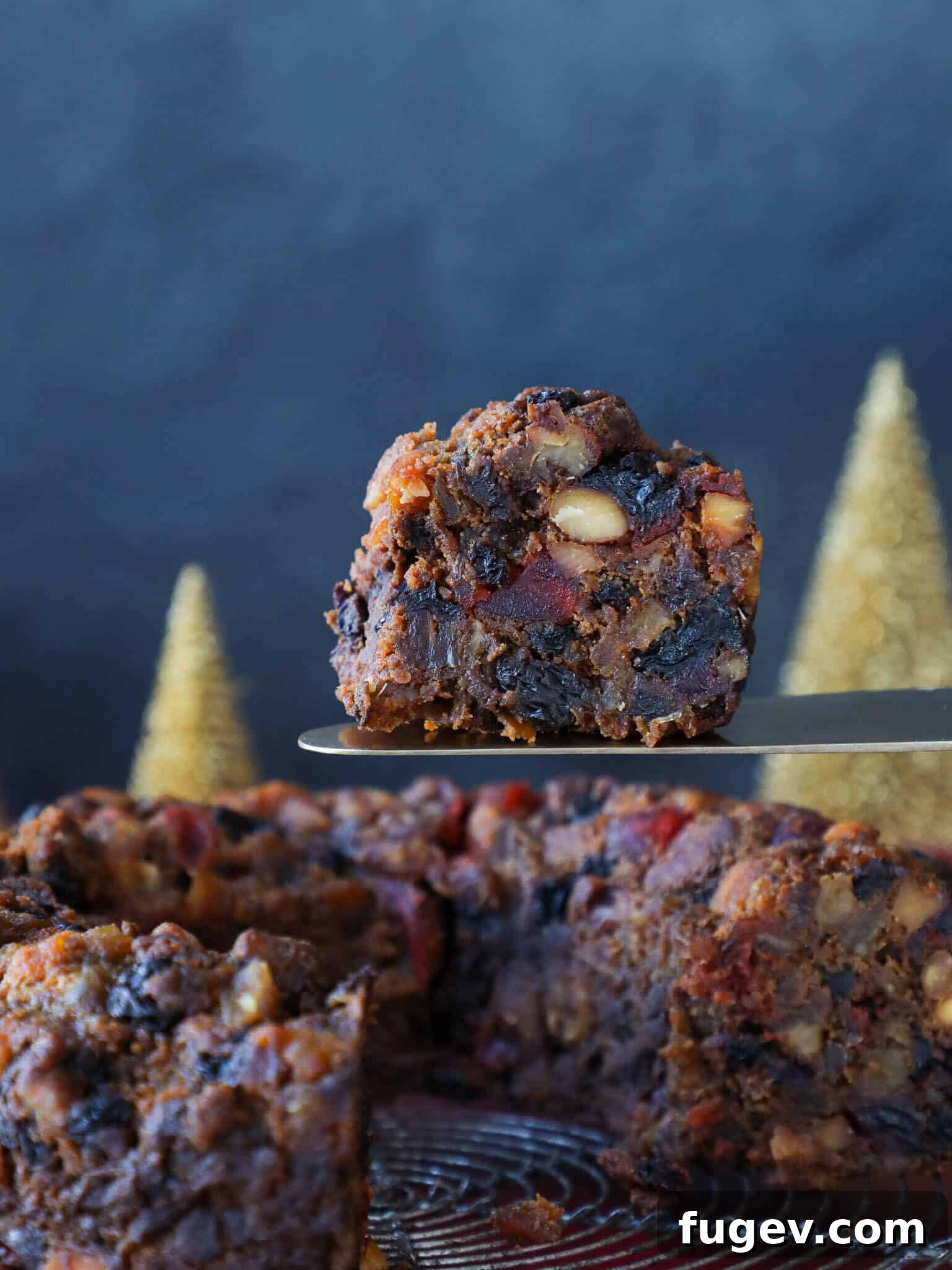 Heritage Fruitcake 2 Old Fashioned Fruit Cake with a rustic blue background, showcasing its rich, dark color and abundance of fruit and nuts