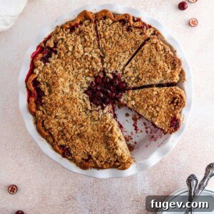 A perfectly sliced cranberry crumble pie, revealing its rich ruby red filling and inviting crumb topping.