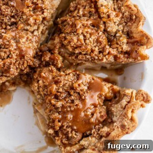 A generous slice of Dutch caramel apple pie, showing off its rich apple filling and crumbly caramel topping.