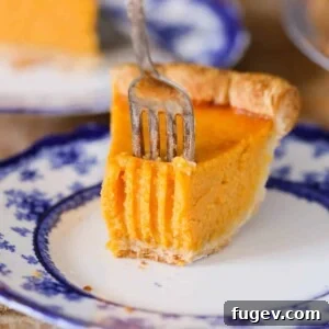 A close-up of one slice of Mary Randolph's Sweet Potato Pie with a fork, emphasizing its creamy texture and deliciousness.