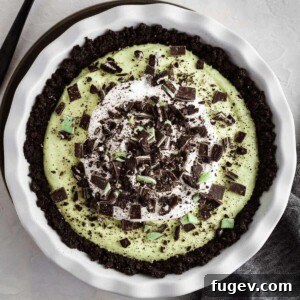 An entire grasshopper pie in a white baking dish, showcasing its vibrant green filling and fluffy whipped cream topping.