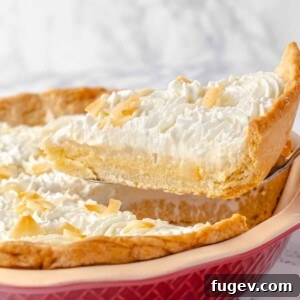 A perfect slice of Coconut Cream Pie gracefully served on a pie server, ready to be enjoyed.