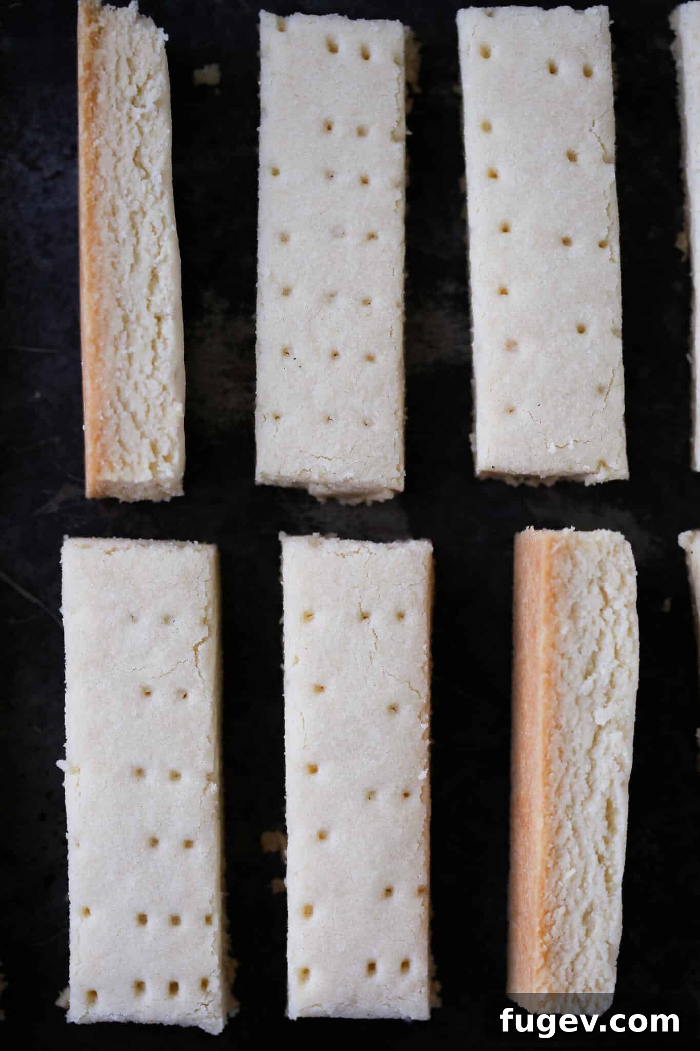 Buttery Scottish Shortbread 2 Scottish shortbread cut into fingers and artfully arranged on a dark background, highlighting its golden-brown edges and delicate texture.