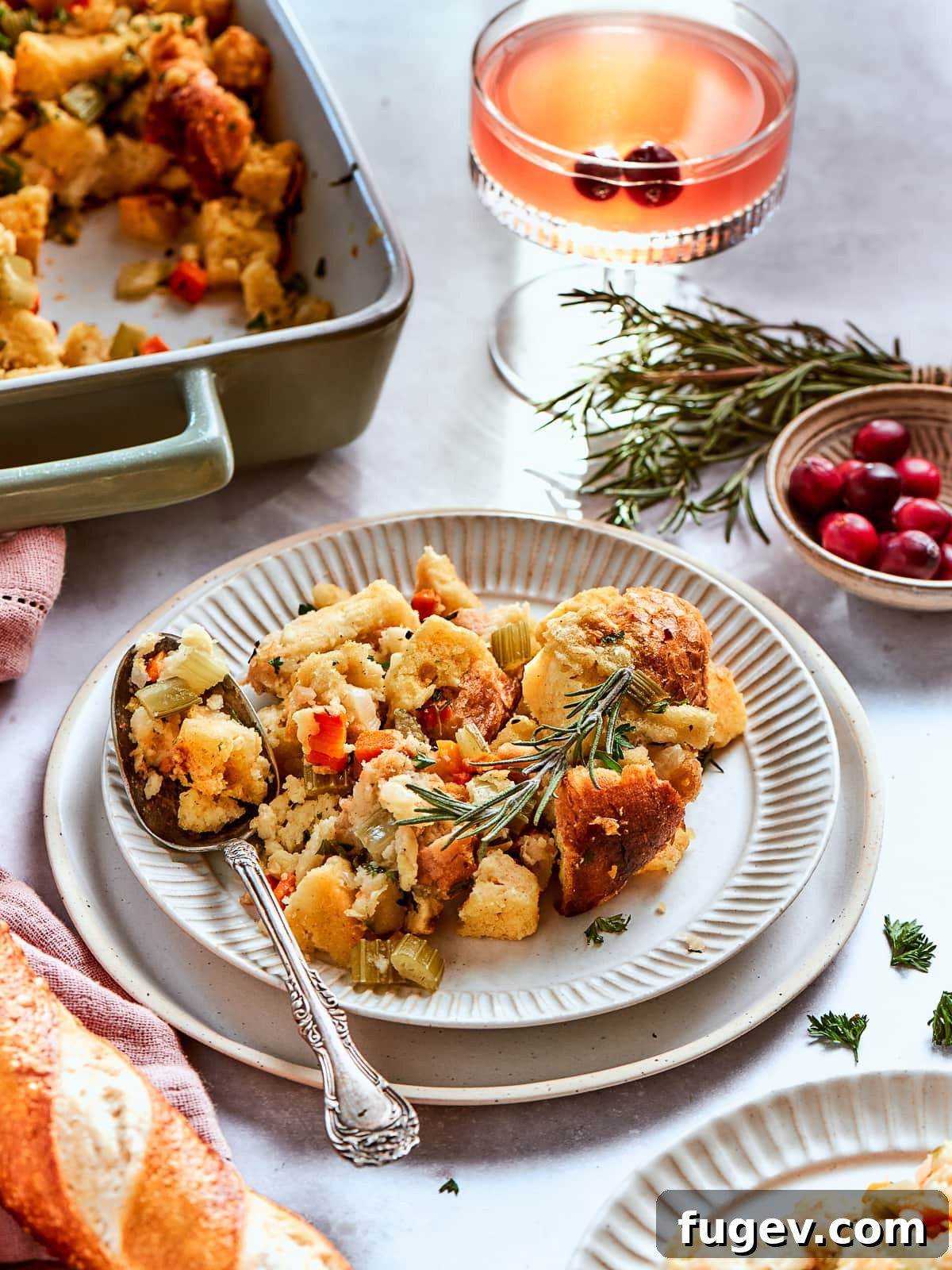 Stress-Free Thanksgiving Recipes 22 A serving dish brimming with golden cornbread dressing, elegantly presented alongside fresh cranberries and seasonal herbs.