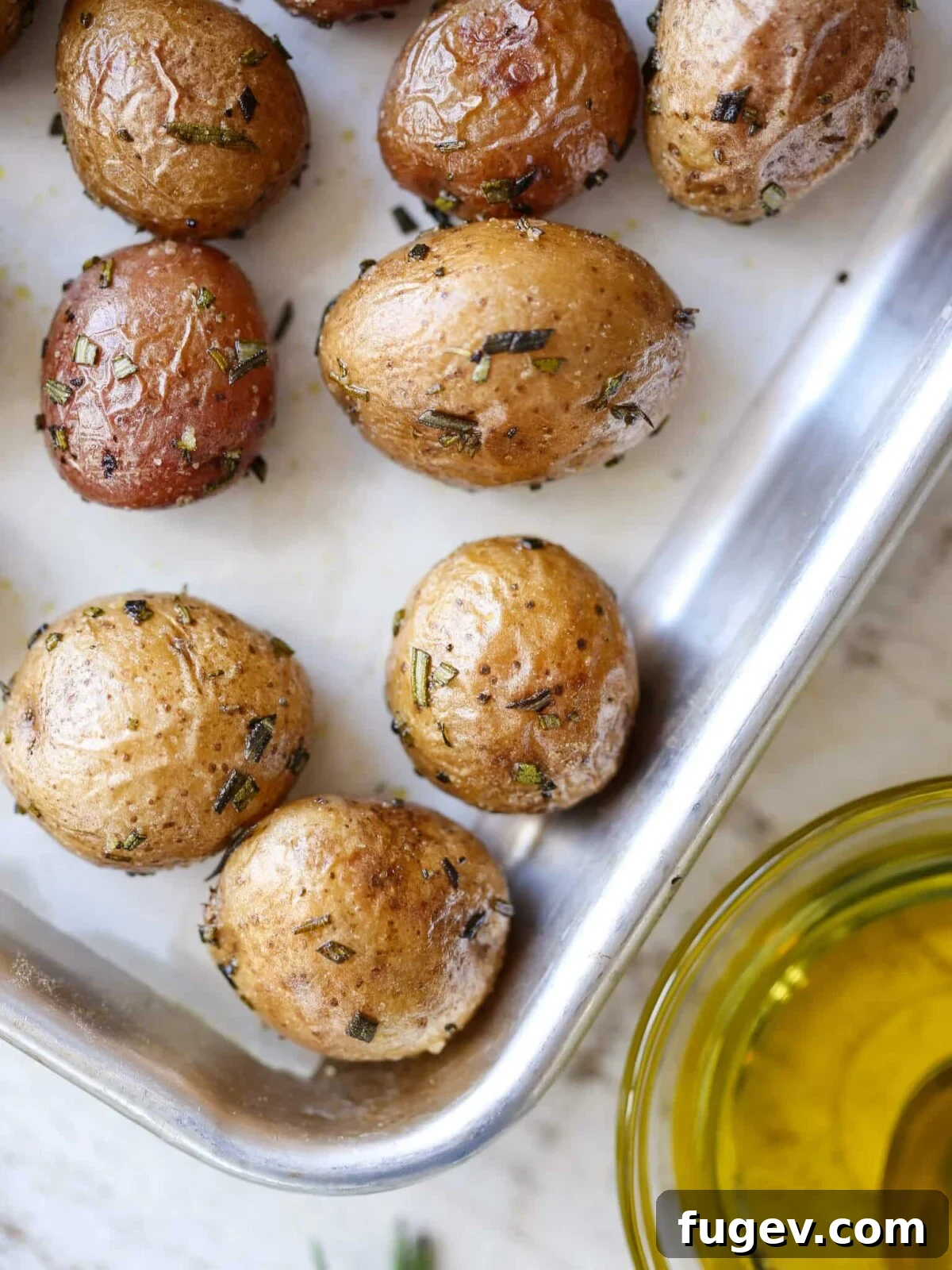 Stress-Free Thanksgiving Recipes 36 Rosemary Roasted Potatoes, glistening with olive oil on a baking sheet, ready for the oven.