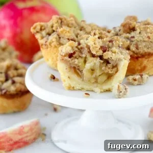 Mini apple pies on a white cake stand, showcasing their perfect bite-sized form.