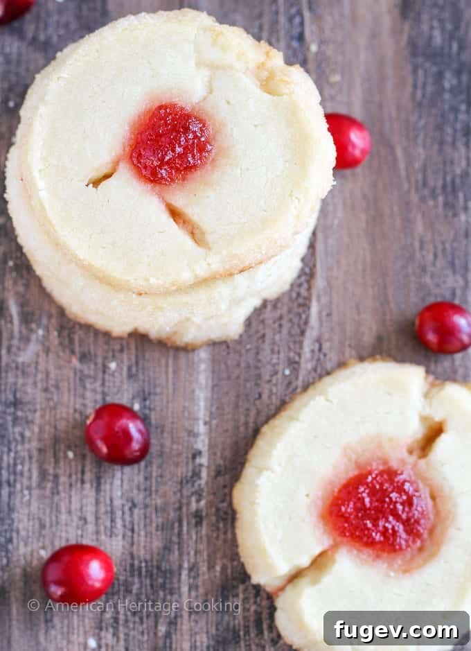 24 Irresistible Christmas Cookies 40 Two cranberry thumbprint cookies on a rustic wooden board, showcasing their vibrant filling.