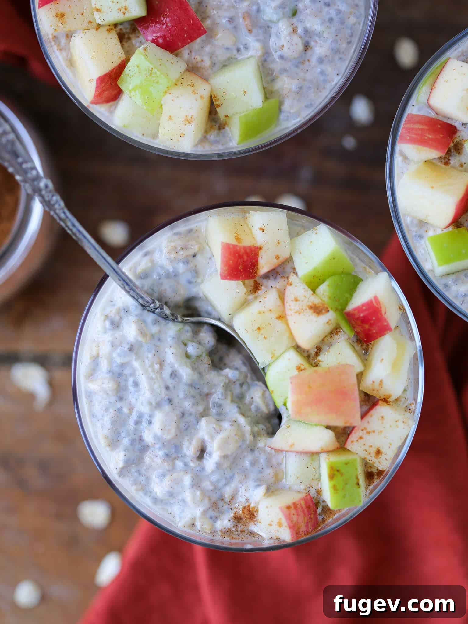 Cozy Apple Pie Overnight Oats 4 A close-up of Apple Pie Overnight Oats in a glass jar, featuring a silver spoon dipped in, highlighting the rich and inviting texture.