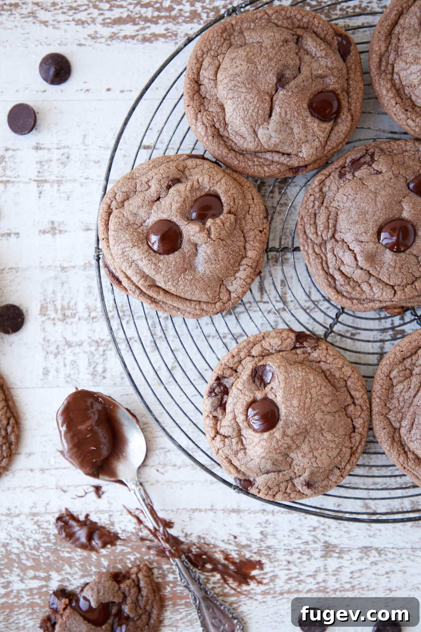Gooey Nutella Cookies 2 Soft and chewy Nutella Chocolate Chip Cookies cooling on a vintage rack, with a jar of Nutella nearby.