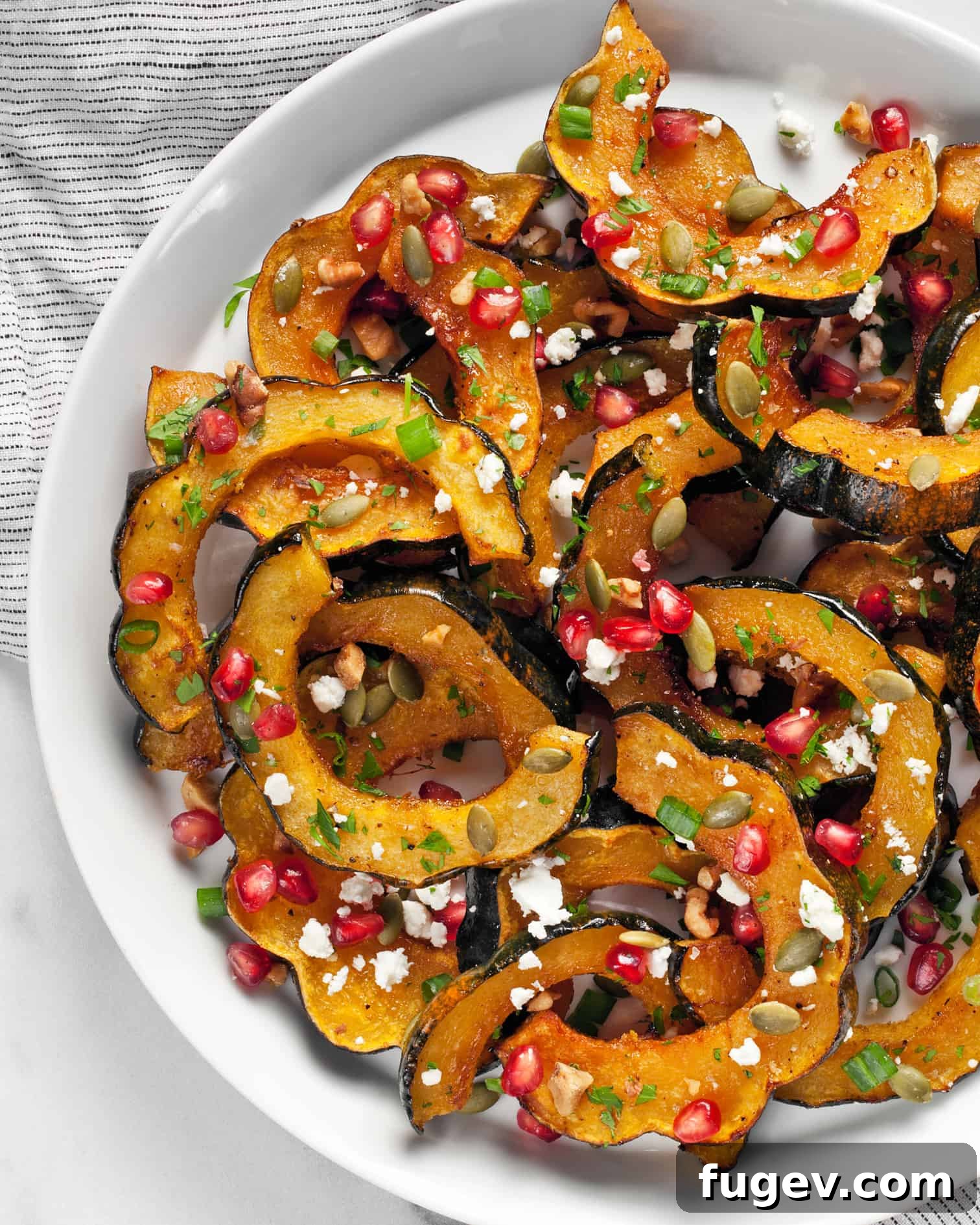 Maple Glazed Acorn Squash 2 Roasted acorn squash slices arranged on a plate, garnished with festive toppings.
