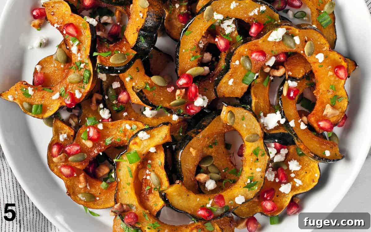 Maple Glazed Acorn Squash 8 Roasted acorn squash topped with pumpkin seeds, pomegranate seeds, goat cheese, and fresh herbs on a white platter.