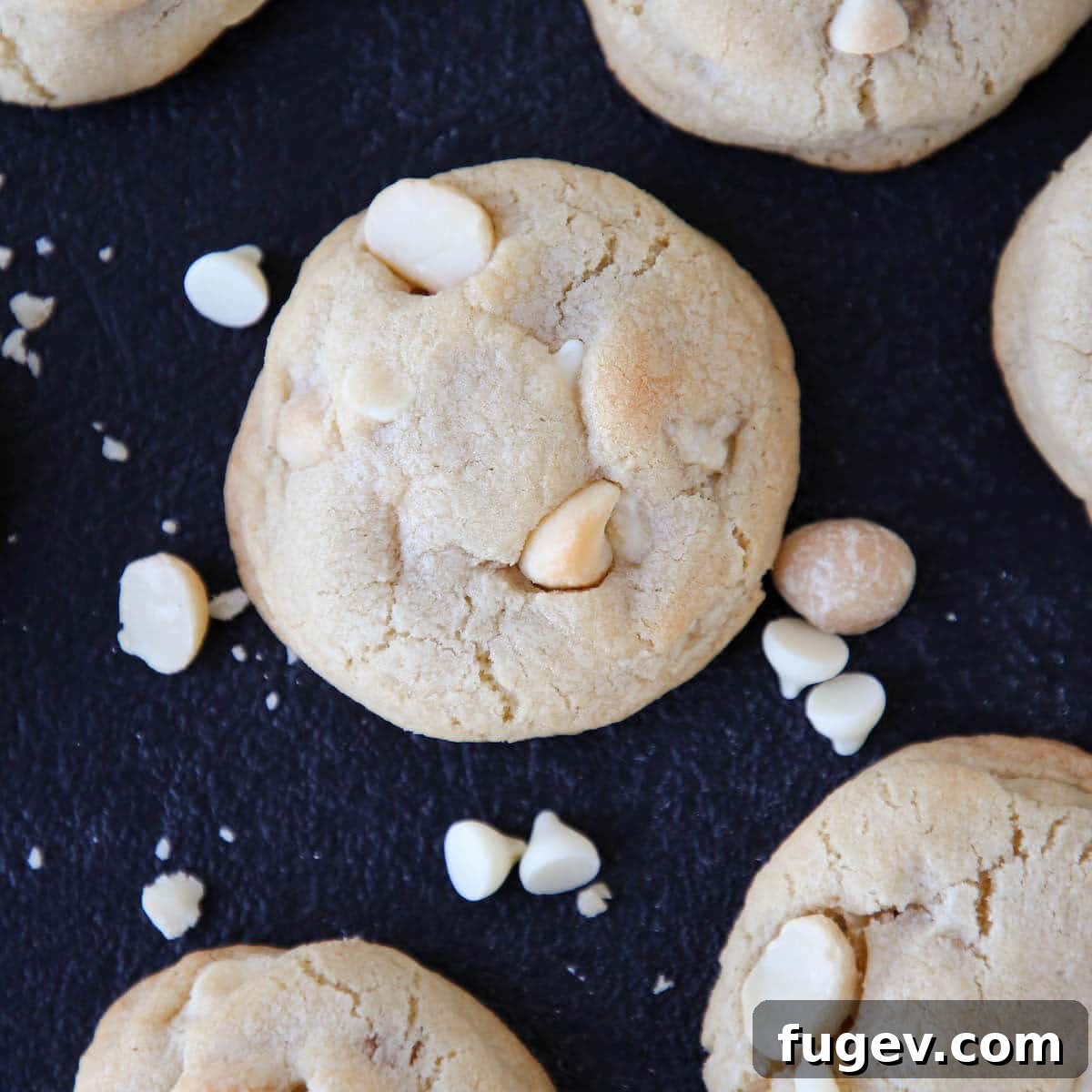 Creamy White Chocolate Macadamia Nut Delights 3 Close-up of baked White Chocolate Macadamia Nut Cookies arranged on a dark countertop.