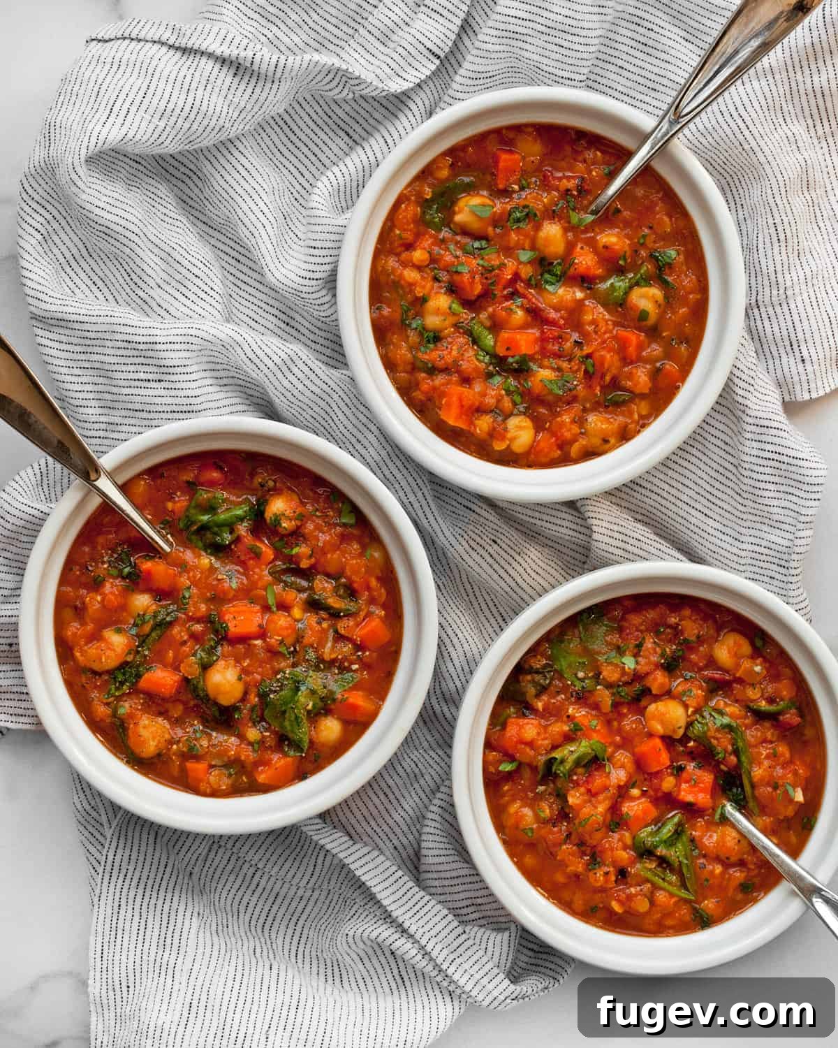 Hearty Red Lentil and Chickpea Soup 2 Three bowls of spicy red lentil and chickpea soup, garnished with fresh herbs, showcasing its rich texture and vibrant color.