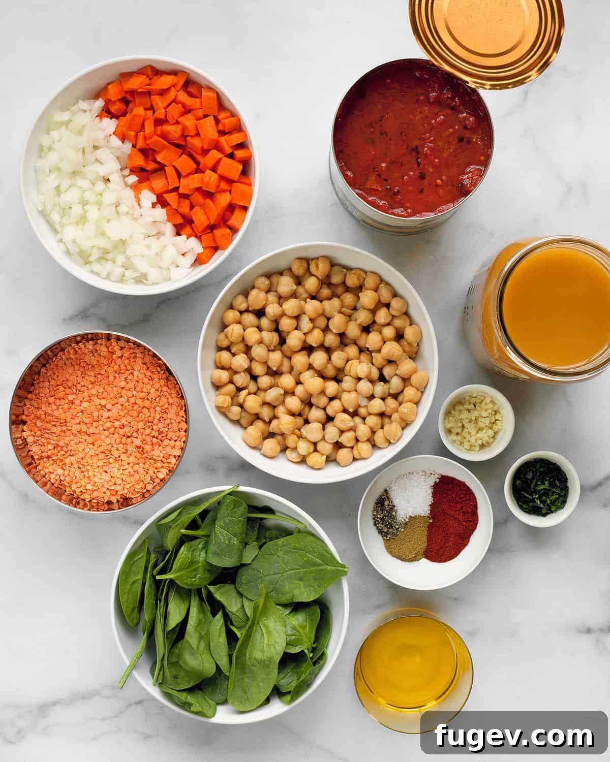 Hearty Red Lentil and Chickpea Soup 3 A flat lay photograph showcasing all the fresh ingredients for red lentil soup: red lentils, chopped carrots, fresh spinach, diced onions, olive oil, minced garlic, and a selection of aromatic spices.